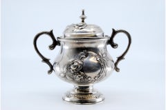 Silver sugar bowl with floral reliefs and set on a round, engraved base
