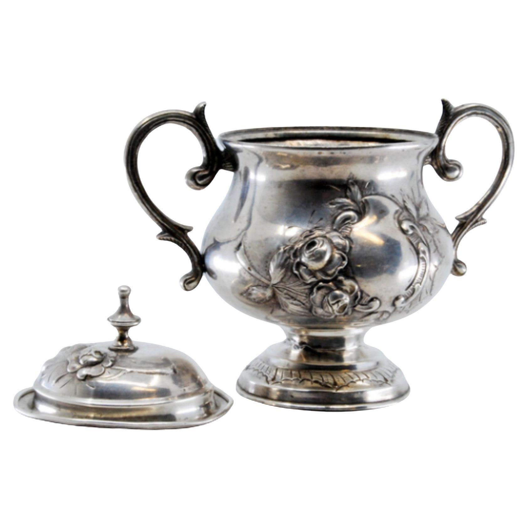 Silver sugar bowl with floral reliefs and set on a round, engraved base