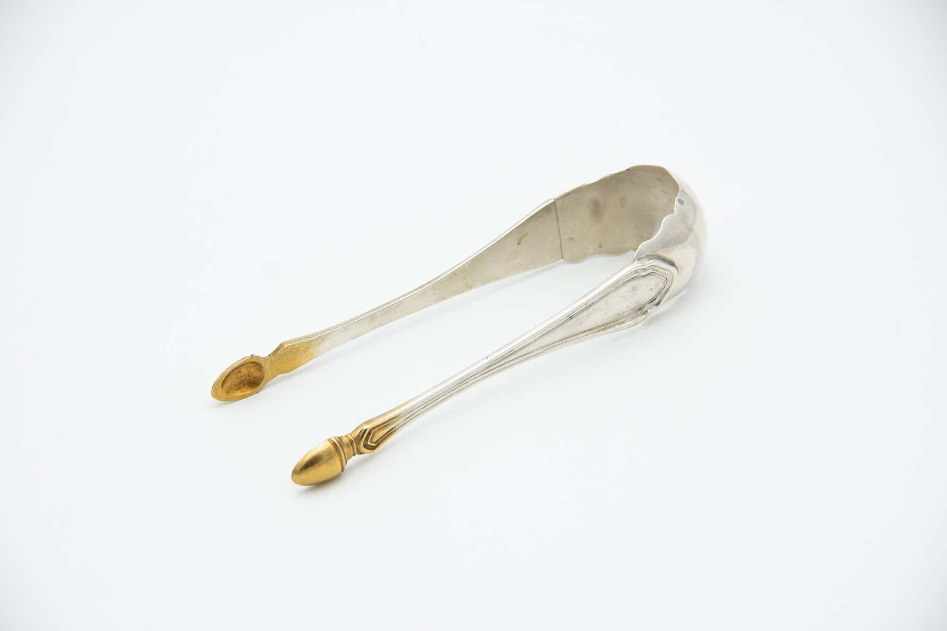 Silver sugar tongs with gold tips