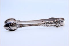 Silver sugar tongs with reliefs surrounding monogram cards