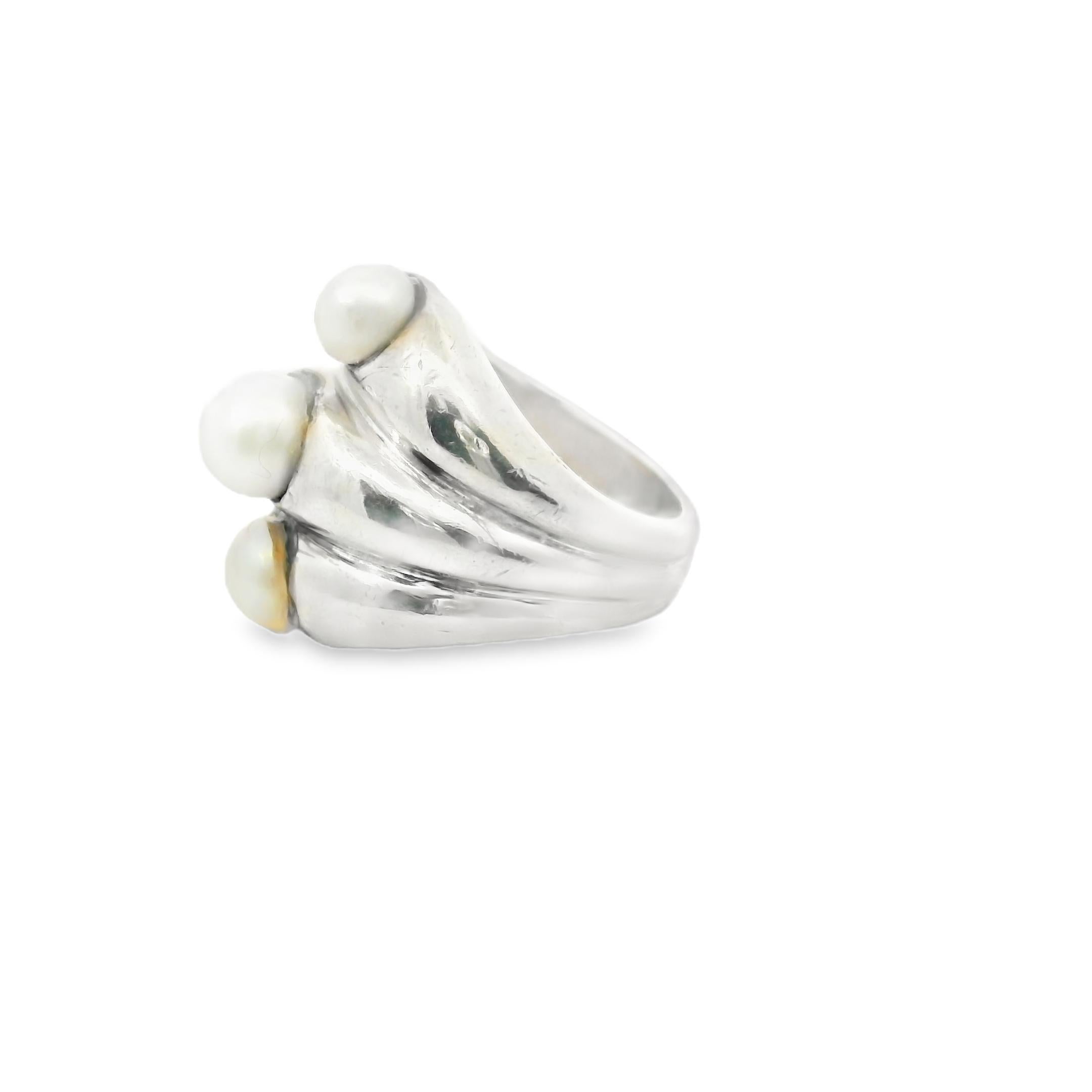 This striking French ring, handcrafted in 1958, is a bold expression of elegance and artistry. Featuring three lustrous white pearls, the design showcases a dynamic arrangement that draws attention to the pearls’ natural beauty while enhancing the