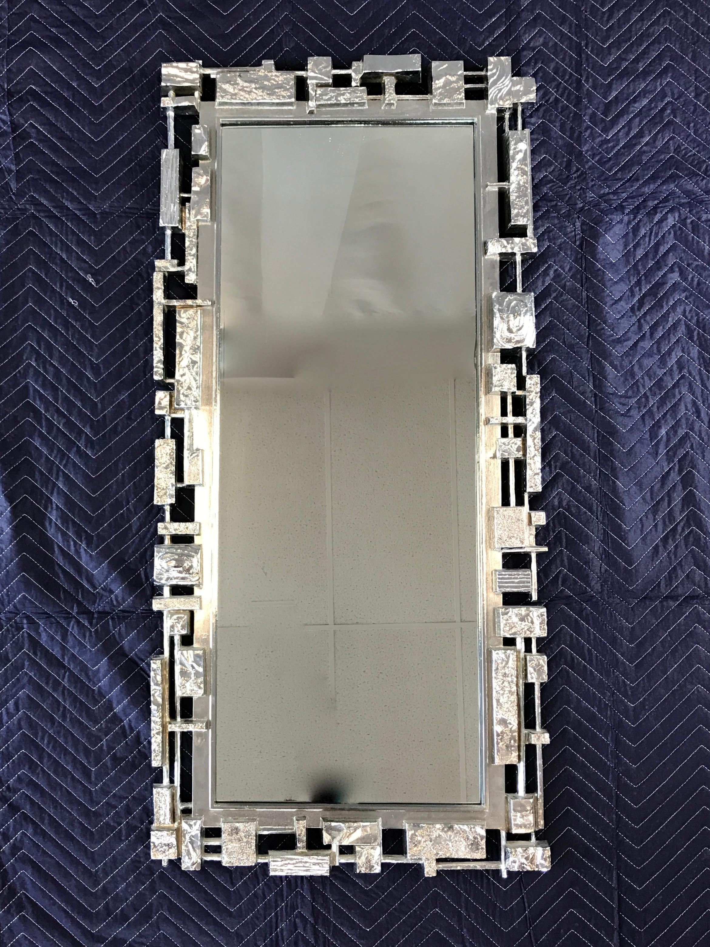 Offer here is a circa 1960s Syroco Brutalist style wall-mounted mirror. By the Syracuse Ornamental Company. Injection molded plastic construction with the outside a type of metallic finish in silver.