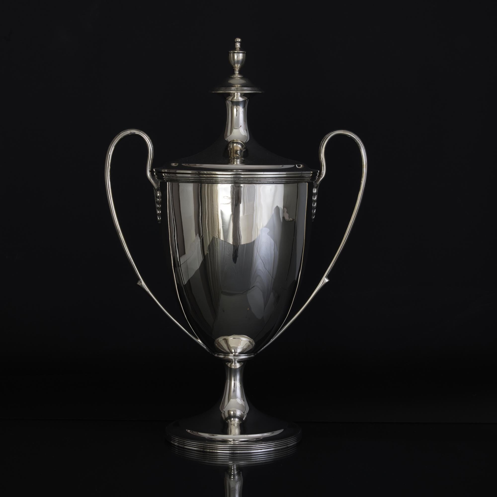 Elegant urn-shaped silver trophy cup and cover in the restrained and graceful neoclassical Adam style with long sweeping handles decorated with a fine thread pattern decoration. Bands of thread decoration surround the body and the spreading silver