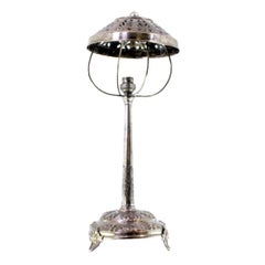 Lampe de table en argent avec des reliefs floraux sur une base circulaire et des pieds en acanthe.