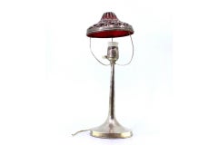 Silver table lamp with red-lined interior, circular base and electrification