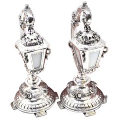 Silver table lamps with suspended globes on relief frames and four-foot bases