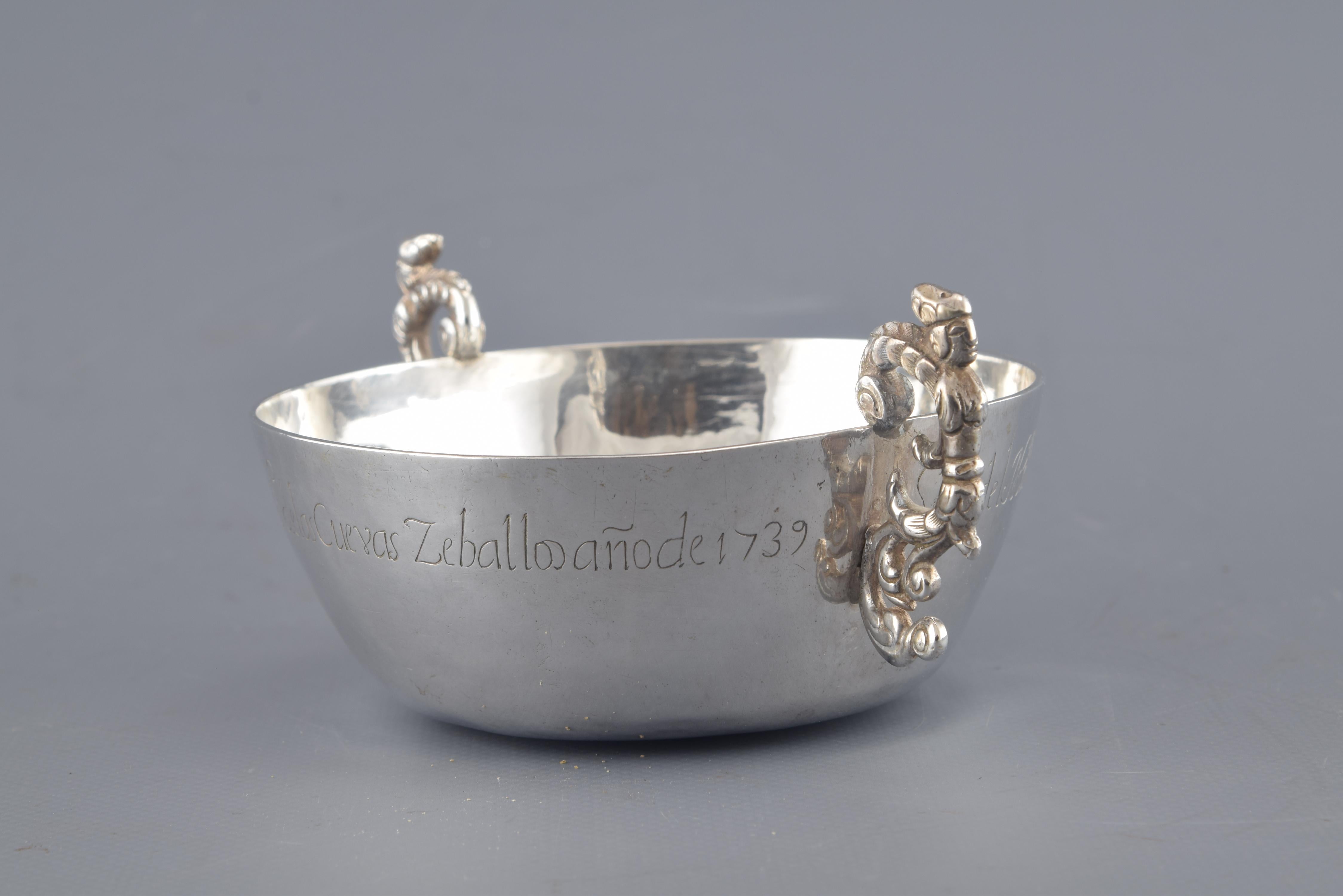 With inscription. Without hallmarks.
Circular “bowl” with smooth mouth and bottom of smaller diameter decorated with two handles (“S” shapped) and an inscription in the outer edge that reads: “Soy del noble conzefo de Santiux de que nos las