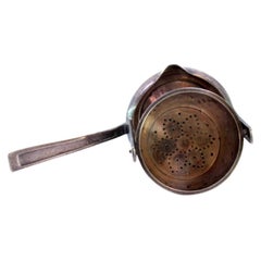 Silver tea strainer w/ tilting cup-shaped container 
handle w/ raised grooves