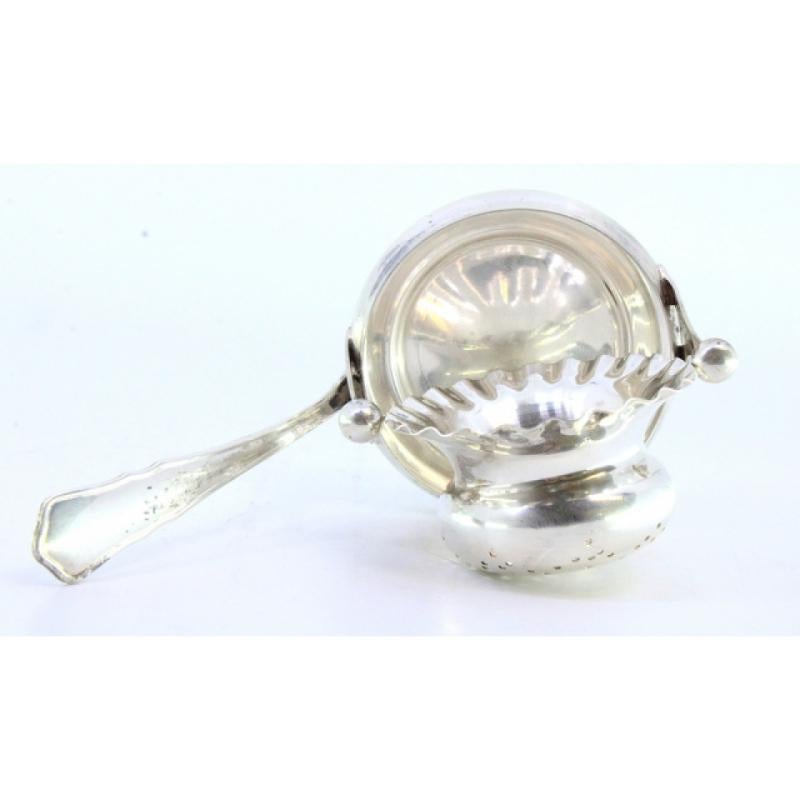 Descrizione: Colino da tè in argento con contenitore a forma di tazza in rilievo e manico a fregio. Metallo: Argento. Origine: Portoghese. Marchio: Cabeça de escravo. Peso: 68,69 grammi. Dimensioni: 12 cm x 6 cm. Contenuto: 833/1000. Marchio di