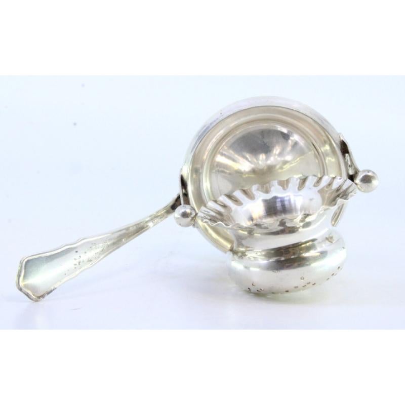 XX secolo Silver tea strainer with bowl-shaped reservoir with reliefs and a frieze handle in vendita