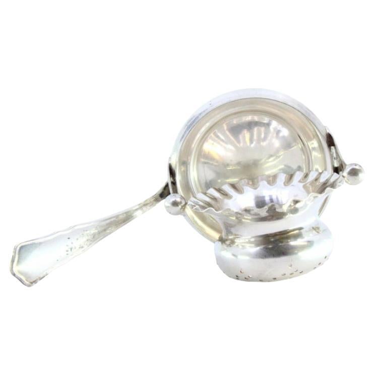Silver tea strainer with bowl-shaped reservoir with reliefs and a frieze handle