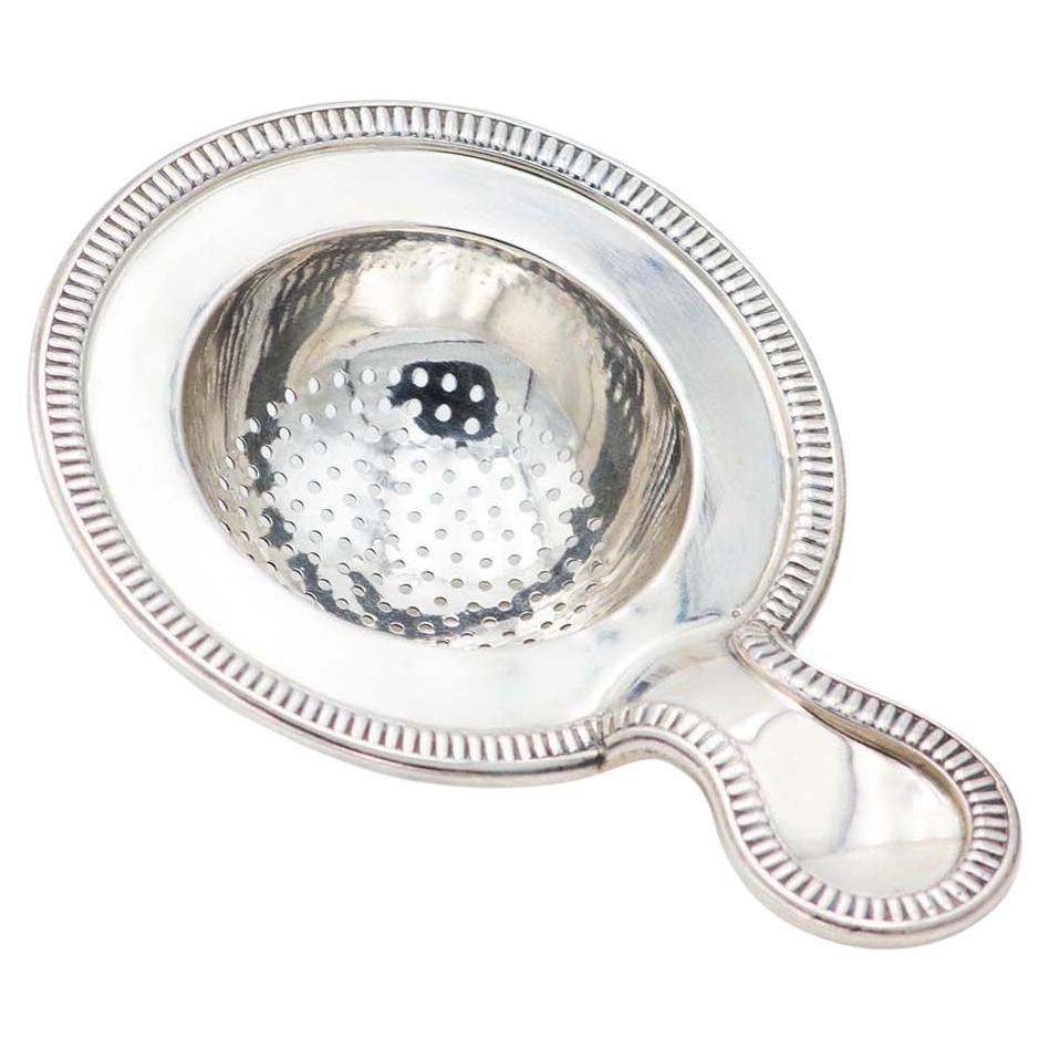Silver tea strainer with relief on the edges