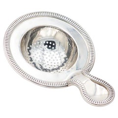 Silver tea strainer with relief on the edges