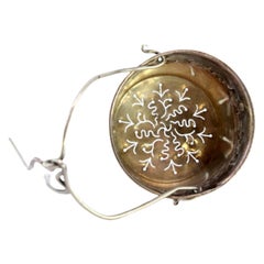 Silver tea strainer with reliefs and hinged handle