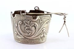 Silver tea strainer with reliefs, cut-out edge and hinged handle
