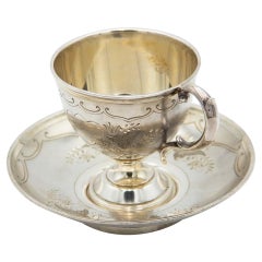 Silver teacup and saucer with floral motifs