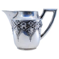 Silberne Teekanne mit erhabenen floralen Motiven und geradem Henkel