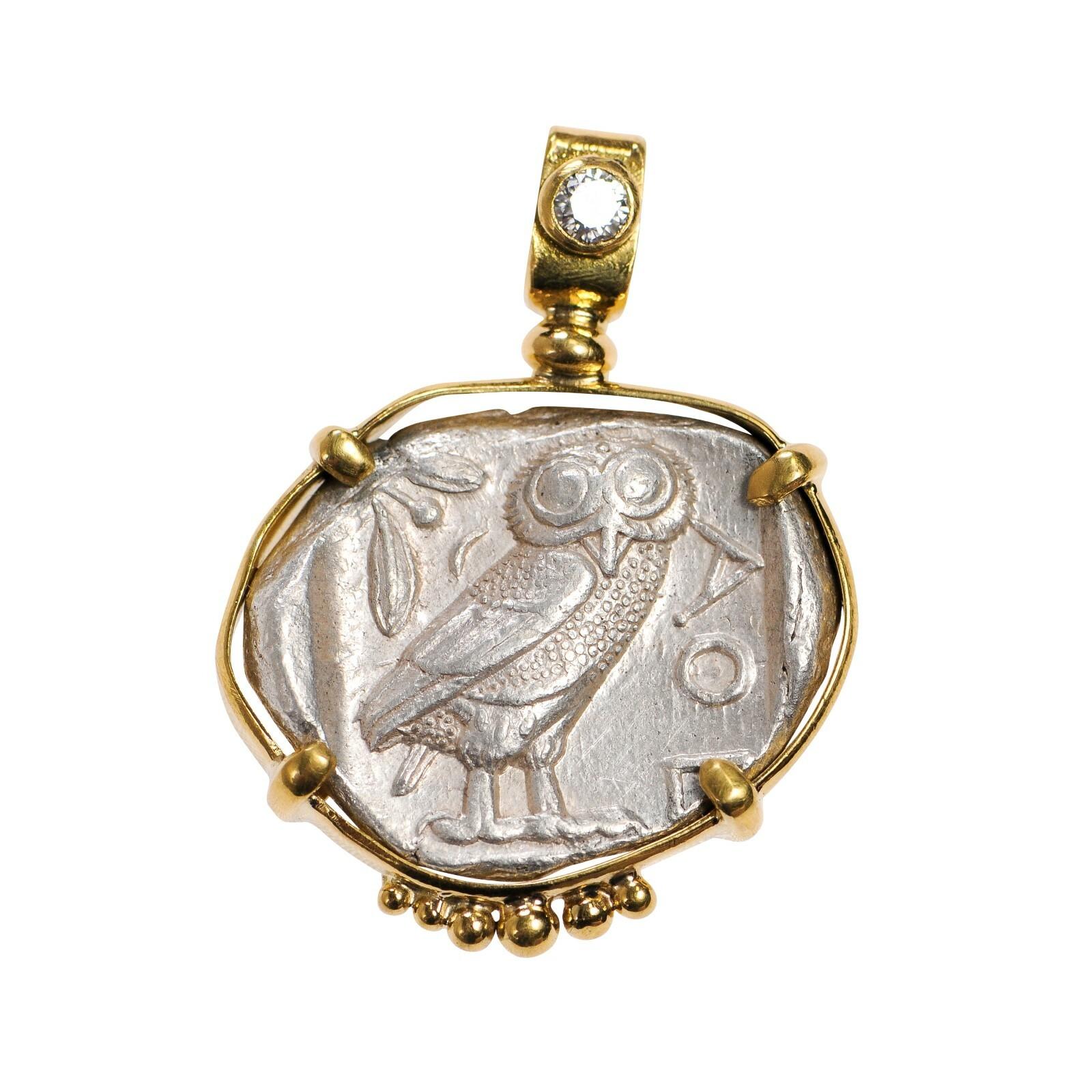 A silver Tetradrachm Owl pendant with Diamond accent and 22 kt gold surround. The delicate gold details add a beautiful touch to this already remarkable Tetradrachm piece. On the reverse side, there is an AOE and owl with an olive sprig and crescent