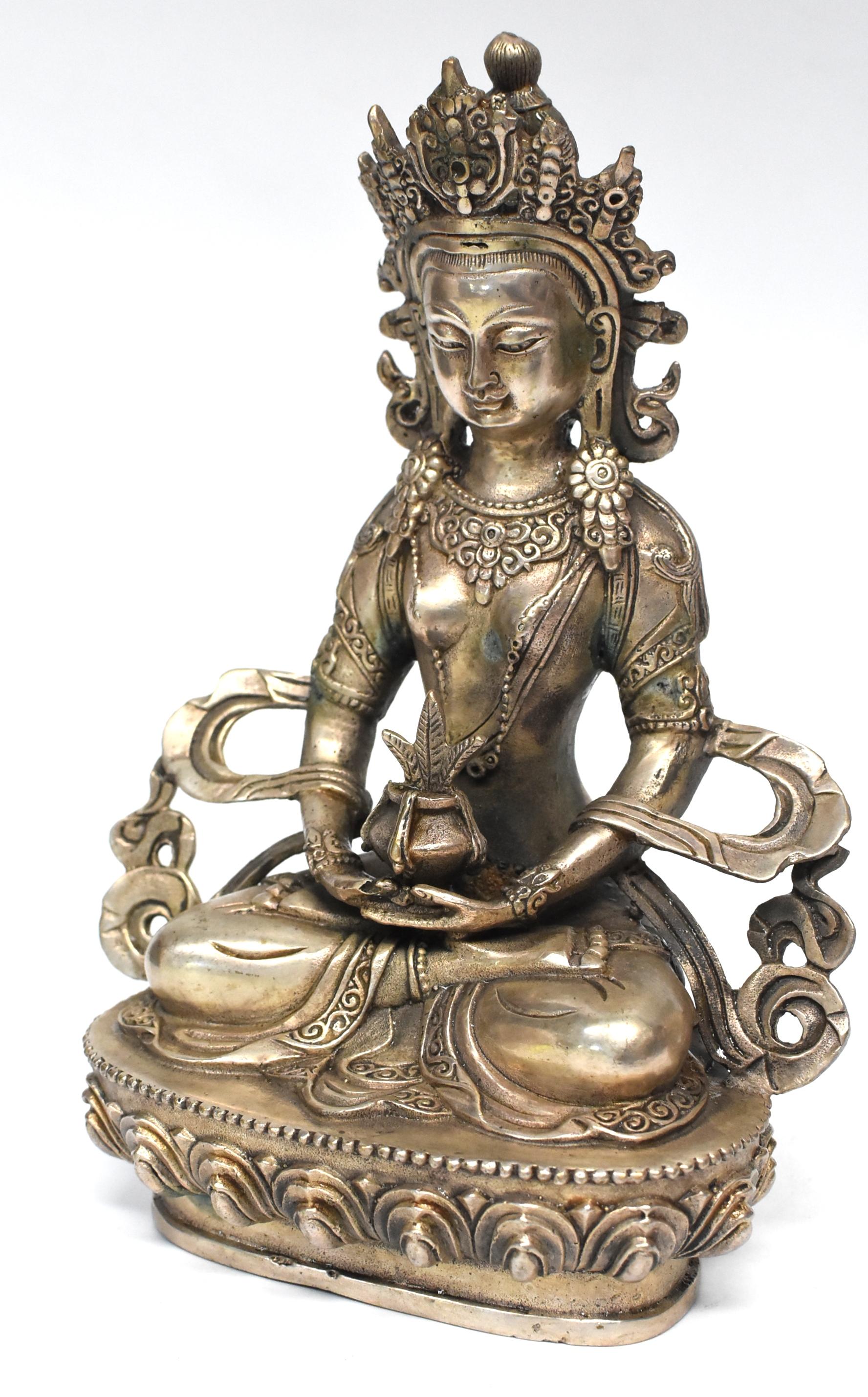 A beautiful silver sculpture of The Tibetan Amitayus, the Bodhissatva/buddha of infinite life, a tantric for of Amitabha, the Buddha of Infinite Light. 
Adorned with necklaces, crown and sashes decorated with rosettes, pearls and medallions, Buddha