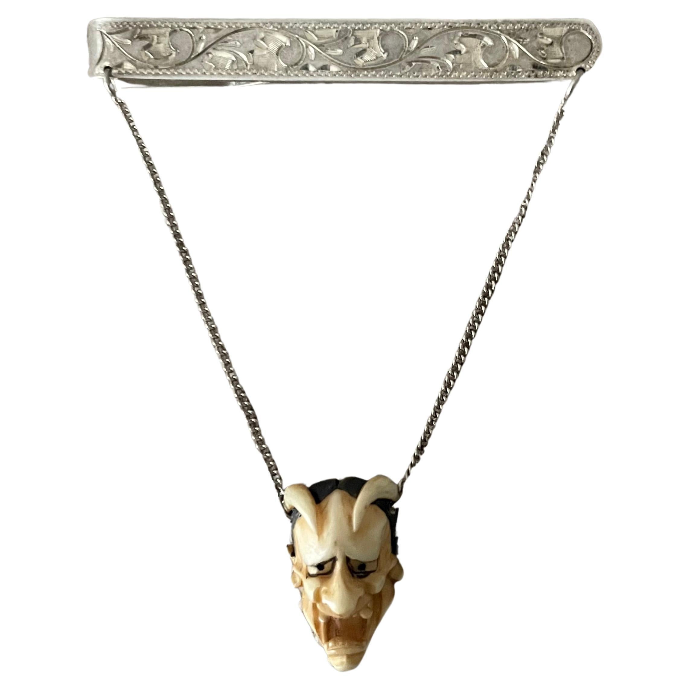 Silver 950 Japanese tie bar with hand painted bone devil Hannya Head.

Two chains from the intricately etched silver bar hold the classic Hannya head. Certainly a conversation starter, also a wonderful decorative piece for the vanity or dresser.