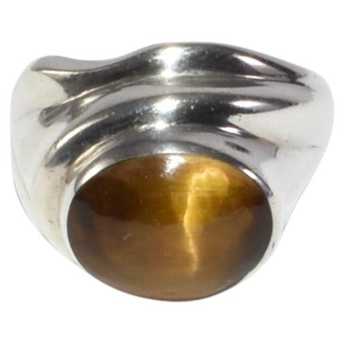 Vintage handmade sculptural silver ring with oval polished tiger's eye cabochon. Signed TAY.

Material: Sterling silver, tiger's eye. 