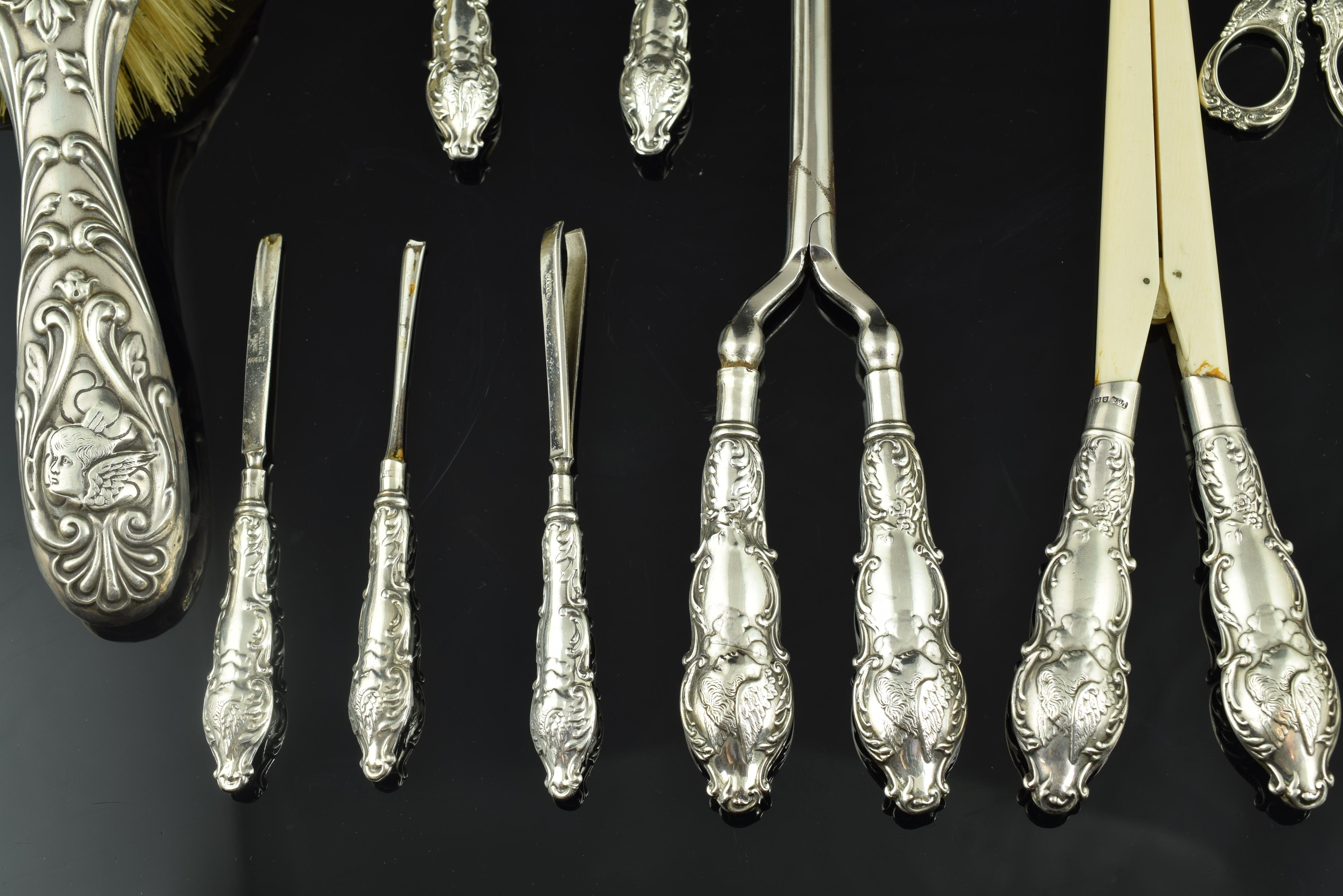 Con segni distintivi.
Set di elementi per la toilette composto da due spazzole, pettine, forbici, pinzette e altri elementi di toelettatura e pettinatura. I manici e i dorsi dei pezzi sono stati decorati con volute, cartigli ed elementi vegetali di