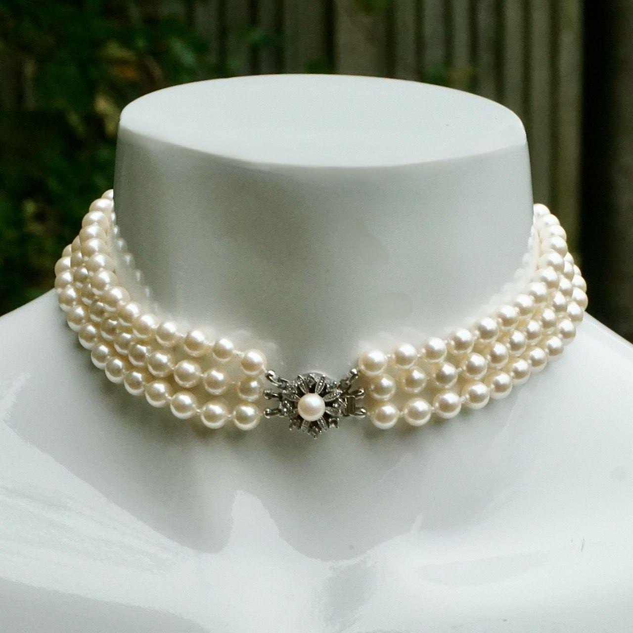 Bellissimo collare in tonalità argento con tre fili di perle finte color avorio e una chiusura rotonda con strass. Le perle sono annodate tra loro. La lunghezza della misura, compresa l'estensione dello strass, è di 37 cm. Il colletto potrebbe
