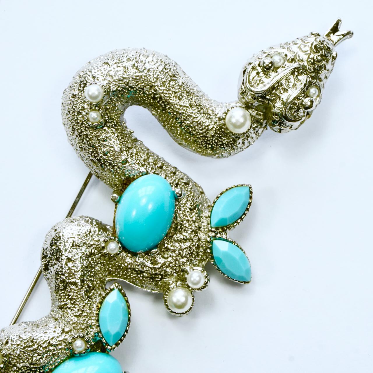 Inusual broche de serpiente texturizada en tono plateado, con detalle de perla de imitación y turquesa de imitación. Mide 12 cm de largo por 4,7 cm de ancho máximo. El broche está en muy buen estado.

Este bonito y detallado broche vintage es de la