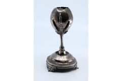 Silver toothpick holder in the shape of a broken egg and fixed on two claws