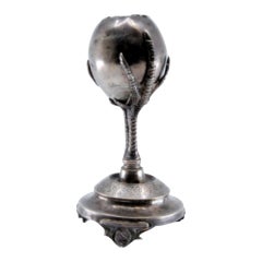 Silver toothpick holder in the shape of a broken egg and fixed on two claws