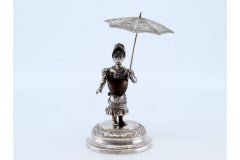 Silver toothpick holder w/ a female figure on a wooden body holding an umbrella