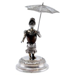 Silver toothpick holder w/ a female figure on a wooden body holding an umbrella