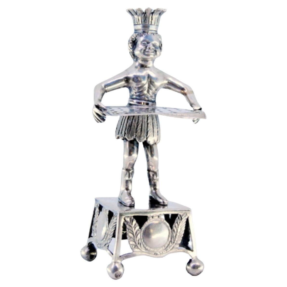 Silver toothpick holder with Indian holding tray and resting on a cut-out plinth
