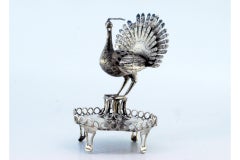 Silver toothpick holder with peacock perched on a base with a wire rack