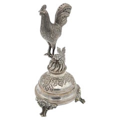 Silver toothpick holder with rooster perched on a flower bed