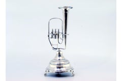 Silver toothpick holder with tuba on pedestal and three leaf-shaped feet