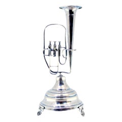 Silver toothpick holder with tuba on pedestal and three leaf-shaped feet