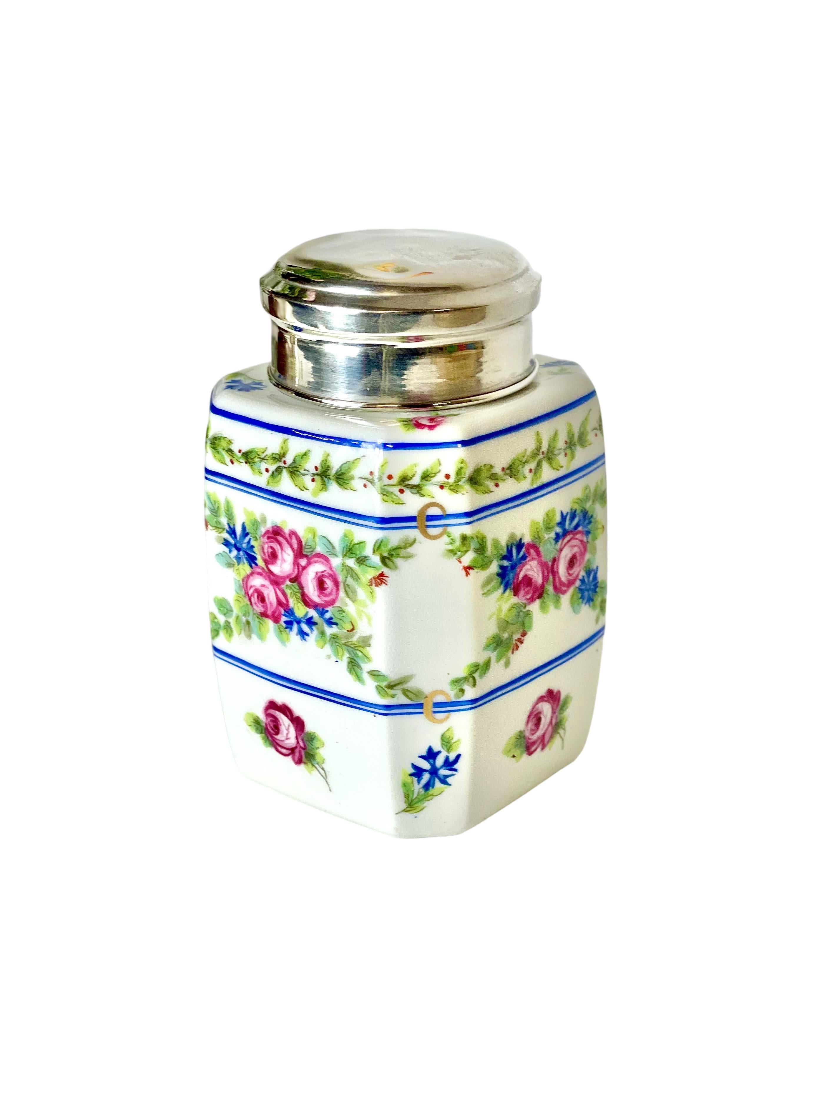 A very pretty silver-topped jar in Limoges porcelain, featuring a fresh and delicate hand-painted design of wild rosebuds, cornflowers and hawthorn branches, enclosed within concentric bands of cobalt blue. The lid is easily removable, making it an