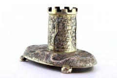 Silver tower-shaped pen holder resting on a base with four half-ball feet