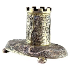 Silver tower-shaped pen holder resting on a base with four half-ball feet