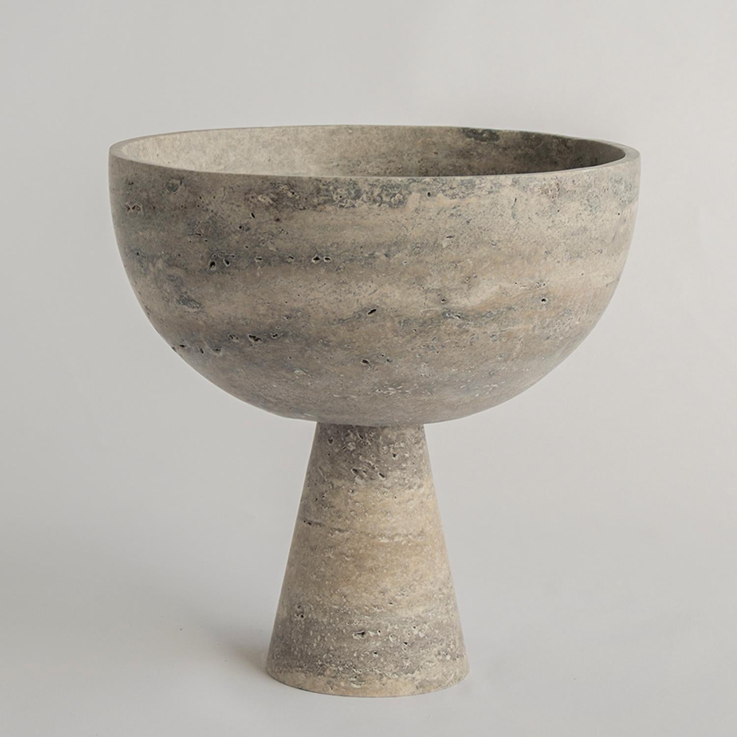 A substantial silver travertine bowl with unique structure rests atop a pedestal for a grand presentation of fruits and vegetables. 

Due to the nature of the material, each piece may vary slightly in appearance. We encourage embracing the