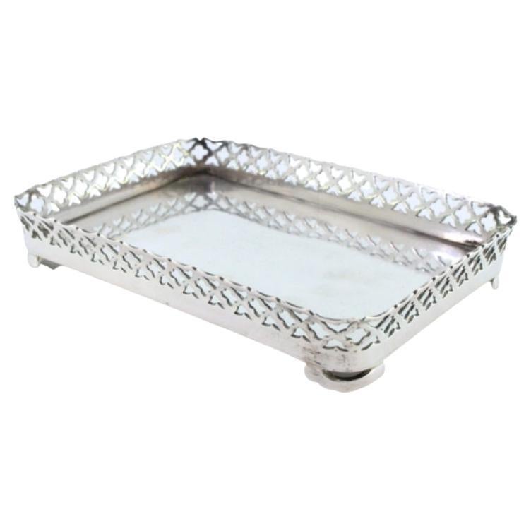 Silver tray with wire rack and smooth base resting on four cut-out feet
