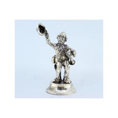 Silver trumpet player waving his hat and sitting on a round beaded base