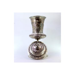 Silver urn with engravings & Cupid-topped lid on round base