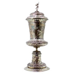Silver urn with engravings 
Cupid-topped lid on round base