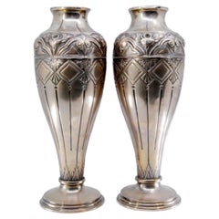 Silver vases with raised floral motifs, shells and circular bases