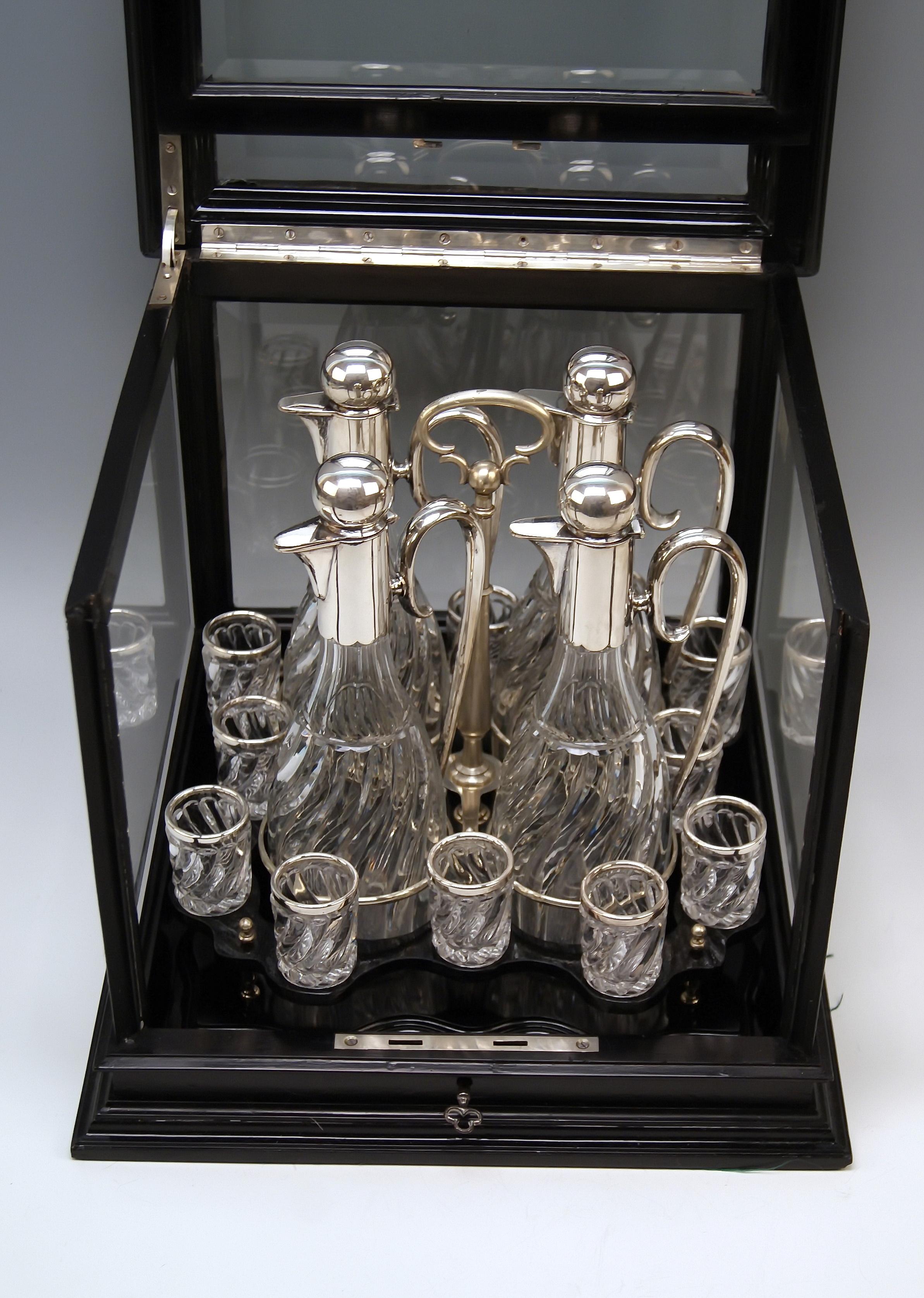 Silver Austrian gorgeous liqueur set of most elegant appearance.

Particular Feature:
Set in original glass case!
Elegant showcase / cabinet with black stained wooden frame. Glassed at five sides (= upper side is glassed, too !). Facet cut glass