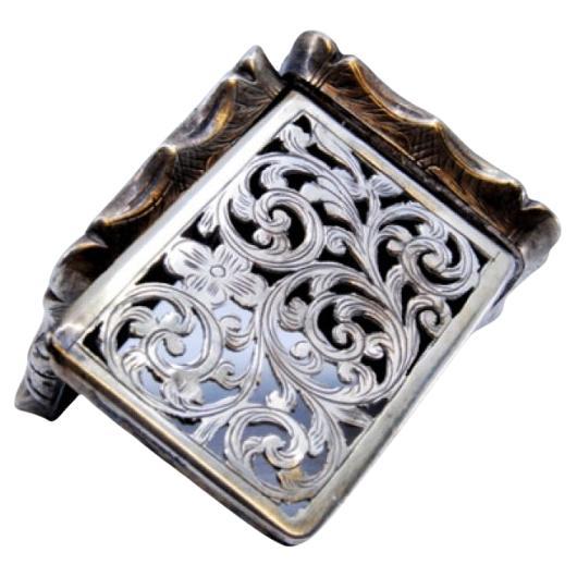 Silver vinaigrette box with scroll engravings and applications on the casing