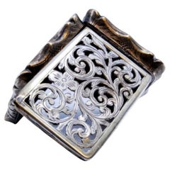 Silver vinaigrette box with scroll engravings and applications on the casing