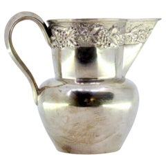 Silver wine jug with grape and leaf reliefs on smooth body